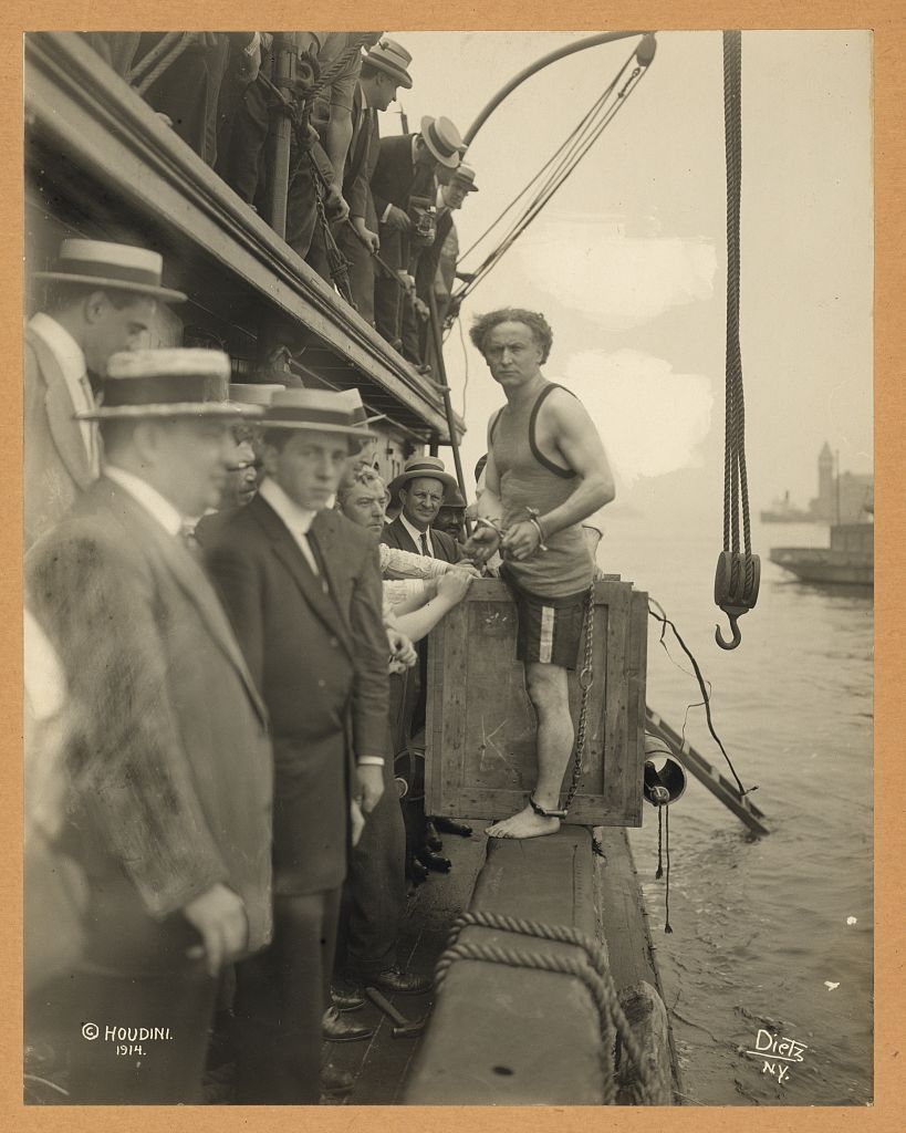 Houdini de pie junto a una caja de madera antes de una escapada en el puerto de Nueva York, en 1912